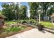 Landscaped backyard featuring a concrete patio and small garden with trees lining the property at 2320 Doster Rd, Monroe, NC 28112