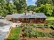 This aerial view shows a brick home with a backyard, a vegetable garden, and mature trees at 2320 Doster Rd, Monroe, NC 28112
