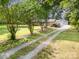 Brick home with metal roof, detached garage, and gravel driveway lined with trees at 2320 Doster Rd, Monroe, NC 28112