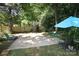 Private backyard with a basketball court, mature trees, and seating area with an umbrella at 2443 Knickerbocker Dr, Charlotte, NC 28212