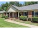 Inviting brick home with covered porch, mature landscaping, and walkway at 2443 Knickerbocker Dr, Charlotte, NC 28212