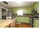Eat-in kitchen featuring light green cabinets, hardwood floors, stainless appliances, and granite countertops at 2443 Knickerbocker Dr, Charlotte, NC 28212