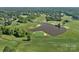 Aerial view of a stunning golf course community with lush greens, a scenic pond, and mature trees at 3506 Cardiff Ln, Matthews, NC 28104