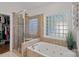 Bathroom featuring a soaking tub with tiled surround and a glass-enclosed shower, perfect for relaxation at 3506 Cardiff Ln, Matthews, NC 28104