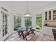 Bright breakfast nook featuring a glass table, wood benches, and many windows showcasing the lush outdoor scenery at 3506 Cardiff Ln, Matthews, NC 28104