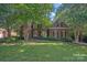 Charming brick home with lush landscaping and mature trees in a well-maintained front yard at 3506 Cardiff Ln, Matthews, NC 28104