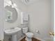 Bright powder room with pedestal sink, a round mirror and a two-piece toilet at 423 Courtland Ct, Kannapolis, NC 28081