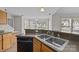 Bright kitchen features wood cabinets, stainless steel sink, and black appliances, offering both style and functionality at 423 Courtland Ct, Kannapolis, NC 28081