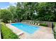 Community pool surrounded by lounge chairs, lush greenery, and a wooden fence at 4329 Hathaway St # D, Charlotte, NC 28211