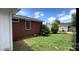View of backyard with brick exterior, partial shed and luscious green grass at 4414 Birkdale Dr, Charlotte, NC 28208