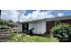 View of backyard with white siding, brick exterior, luscious green grass and overgrown bushes at 4414 Birkdale Dr, Charlotte, NC 28208
