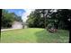 View of backyard with white siding, brick exterior, luscious green grass and a partial shed at 4414 Birkdale Dr, Charlotte, NC 28208