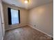 A cozy bedroom includes a window with dark curtains and neutral carpet at 5523 Stone Bluff Ct, Charlotte, NC 28214