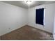 A cozy bedroom includes a window with dark curtains and neutral carpet at 5523 Stone Bluff Ct, Charlotte, NC 28214