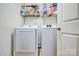 A compact laundry room featuring modern washer and dryer units with storage shelves at 5611 Charter Oaks Ln, York, SC 29745