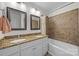 Bathroom featuring a double sink vanity with granite countertop, warm beige tiles, and framed mirrors at 6017 Sierra Dr, Charlotte, NC 28216