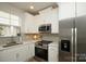 Well-lit kitchen showcasing stainless steel appliances, quartz countertops, white cabinets, and tiled backsplash at 711 Beaty St, Davidson, NC 28036