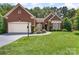 Brick home with a two car garage, manicured landscaping, and mature shade trees at 7211 Baniff Cir, Charlotte, NC 28277