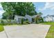 View of the gray home with a long concrete driveway and well-manicured landscaping at 7901 Reames Rd, Charlotte, NC 28216