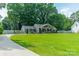 Landscaped front lawn with gray home, driveway, and wooden fence along the property line at 7901 Reames Rd, Charlotte, NC 28216
