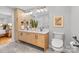 Bathroom featuring a double sink vanity with light wood cabinets, gray tile flooring, and toilet at 7916 Wellston Dr, Charlotte, NC 28210