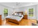 Inviting main bedroom with wood floors, ceiling fan, two windows, and & nightstands at 7916 Wellston Dr, Charlotte, NC 28210