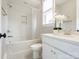 A white bathroom featuring a shower-tub combo, sink with marble countertop, and window with flowers at 1008 Ladera Dr, Waxhaw, NC 28173