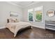Bright bedroom featuring hardwood floors, large windows, and minimalist decor for a serene and inviting atmosphere at 1008 Ladera Dr, Waxhaw, NC 28173
