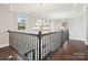 Upper hallway featuring dark hardwood floors, elegant wrought iron railings, and stylish chandelier lighting at 1008 Ladera Dr, Waxhaw, NC 28173