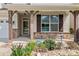 Close-up of the front porch with stone accents, a storm door, and manicured landscaping at 112 Artisan Ct, Mooresville, NC 28117