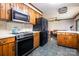 Kitchen has wood cabinets, appliances, and ceiling fan looking into the living room at 1142 Foxberry Rd, Lincolnton, NC 28092