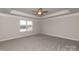 Spacious bedroom with carpet, ceiling fan, tray ceiling, and large window overlooking neighborhood at 115 Kerr Walk Dr # 37, Statesville, NC 28677