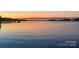 Idyllic lakeside view featuring a tranquil lake, a boat dock, and a colorful sunset backdrop at 14515 Nc Hwy 73 Hwy, Huntersville, NC 28078