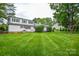 Expansive backyard featuring lush green grass, mature trees, and a charming white house with blue shutters at 1506 Cameron Dr, Statesville, NC 28625