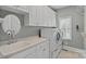 Well-equipped laundry room with modern washer, dryer, sink, and ample cabinet space at 17308 Players Ridge Dr, Cornelius, NC 28031