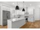 Modern kitchen features stainless steel appliances, white cabinetry, large island with quartz countertop at 2004 St John St, Charlotte, NC 28216