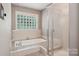 Bright bathroom with soaking tub, tiled floor, and glass block window at 2234 Hamilton Mill Rd, Charlotte, NC 28270