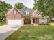 Charming brick home showcasing a well-manicured lawn, attached garage, and inviting entrance at 2608 Golden Bell Dr, Gastonia, NC 28056