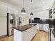 Island kitchen with stainless steel appliances, white cabinets, and black countertops at 3459 Selwyn Ave, Charlotte, NC 28209
