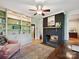 Sunny sunroom featuring built-in shelving, a dark brick fireplace, and hardwood floors at 3459 Selwyn Ave, Charlotte, NC 28209