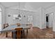 Open dining area with hardwood floors features a modern table and views of the entryway and kitchen at 3801 Rosedown Dr, Matthews, NC 28105