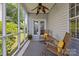 Relaxing screened porch with rocking chairs, ceiling fan, and wooded view, creating a cozy outdoor space at 3801 Rosedown Dr, Matthews, NC 28105