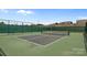 Well-maintained tennis court featuring a green surface and a tall net, surrounded by fencing and trees at 4117 Bright Rd, Charlotte, NC 28214