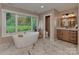 Bright bathroom featuring a soaking tub, large window with backyard views, and modern vanity at 4201 Quail Hunt Ln, Charlotte, NC 28226