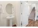 Well-lit half bath with a pedestal sink, mirror, and access to the staircase at 449 Misty Law Ln, Clover, SC 29710