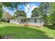 View of the house from the rear showing a side porch and lawn with mature trees and blue sky at 4648 Rifle Range Rd, Conover, NC 28613