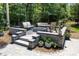 Custom stone patio featuring built-in seating around a cozy fire pit in a private backyard setting at 5088 Watersail Way, Clover, SC 29710