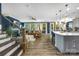 Open-concept living room with hardwood floors, modern kitchen, brown leather sofa and stylish furnishings, illuminated by natural light at 5088 Watersail Way, Clover, SC 29710
