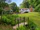 Lush backyard view featuring a fire pit with Adirondack chairs, detached garage and a small wooden bridge at 607 Coulwood Dr, Charlotte, NC 28214