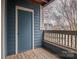 A balcony with blue siding, a door, and wooden floors overlooks a parking lot and trees at 623 Olmsted Park Pl # D, Charlotte, NC 28203